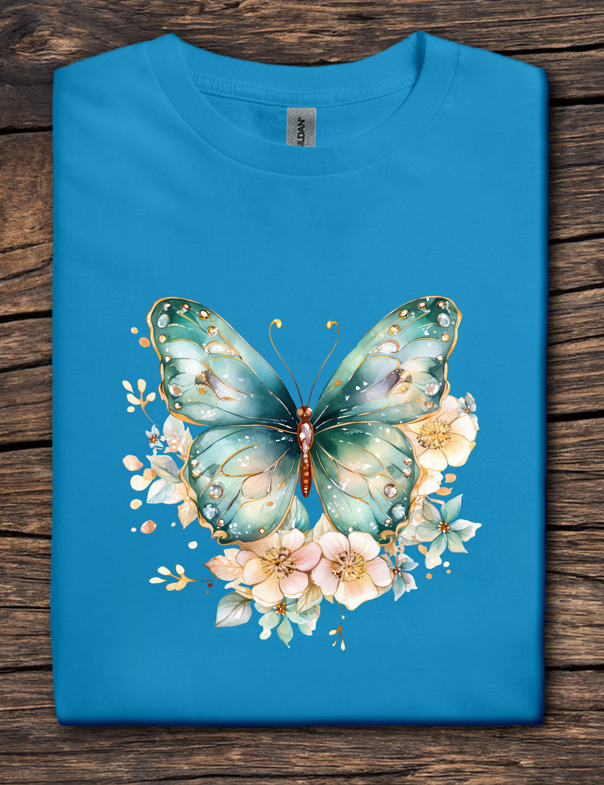 Blue t-shirt with a green butterfly and floral design on a wooden surface