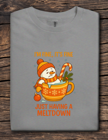 Gray t-shirt with a snowman in a hot chocolate cup graphic and text on a wooden surface