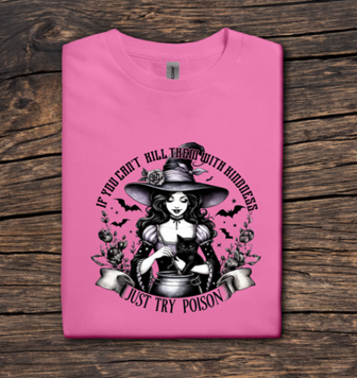 Pink t-shirt with a witch graphic and text on a wooden surface