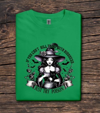Green t-shirt with a witch graphic and text on a wooden surface