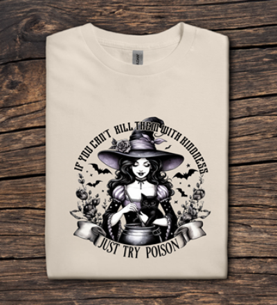 Beige t-shirt with a witch graphic and text on a wooden surface
