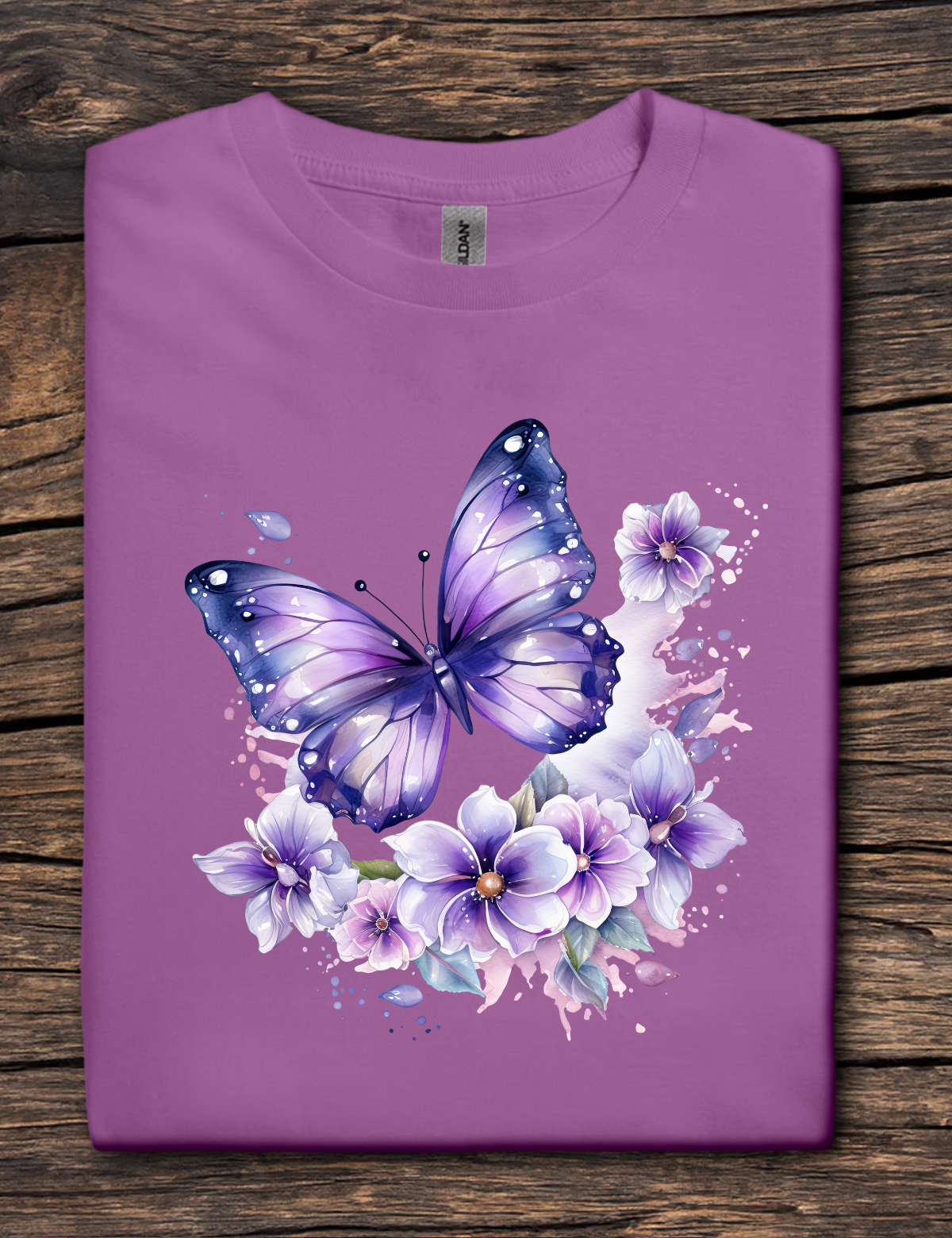 Purple t-shirt with a butterfly and floral design on a wooden surface