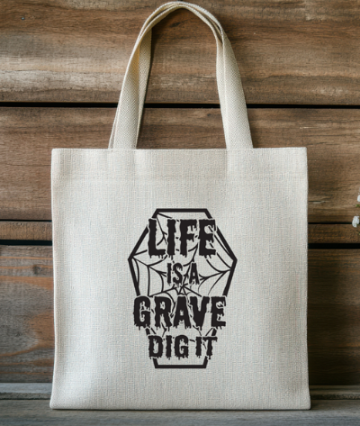 Tote bag with 'Life is a Grave Dig It' design on a wooden background