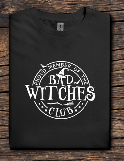 Black t-shirt with 'Proud Member of the Bad Witches Club' text on a wooden surface