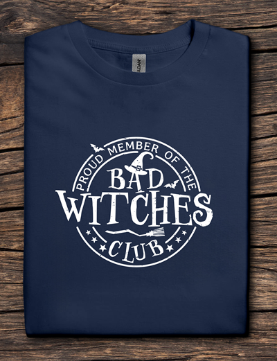 Navy blue t-shirt with 'Proud Member of the Bad Witches Club' text on a wooden surface