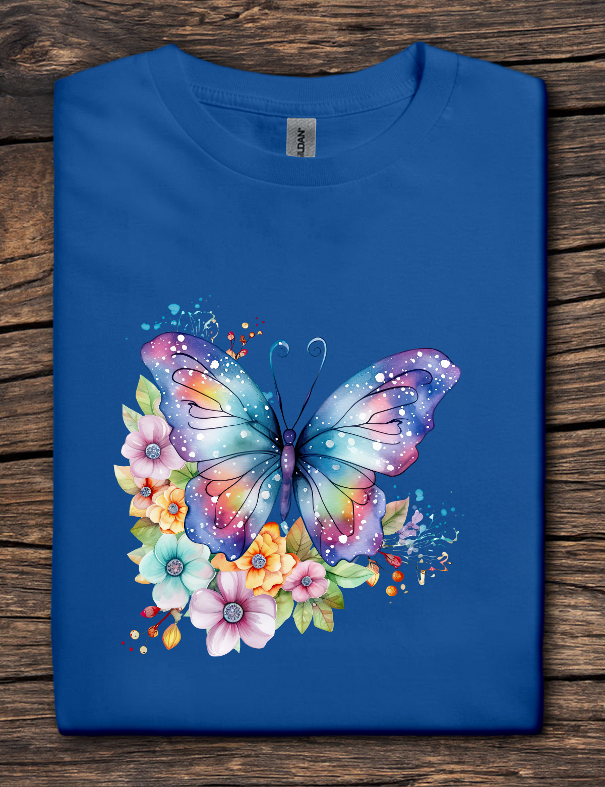 Blue t-shirt with a colorful butterfly and floral design on a wooden surface