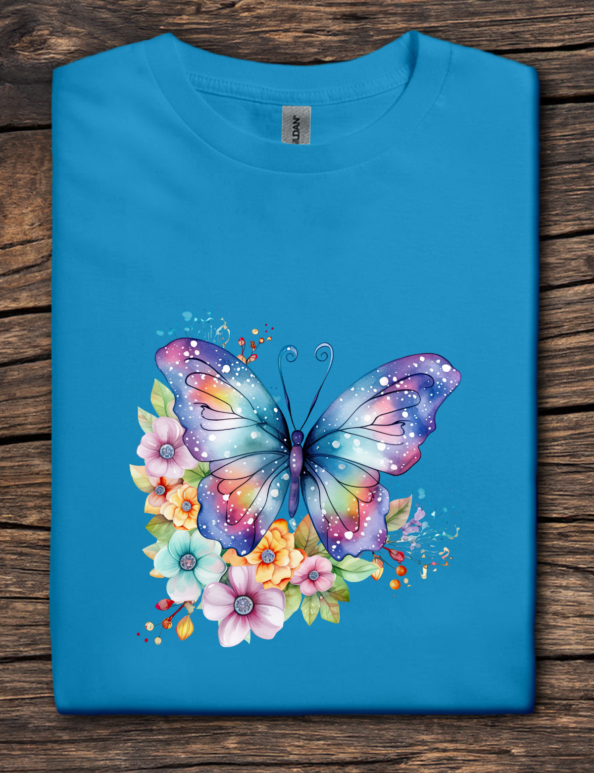 Blue t-shirt with a colorful butterfly and flowers design on a wooden surface